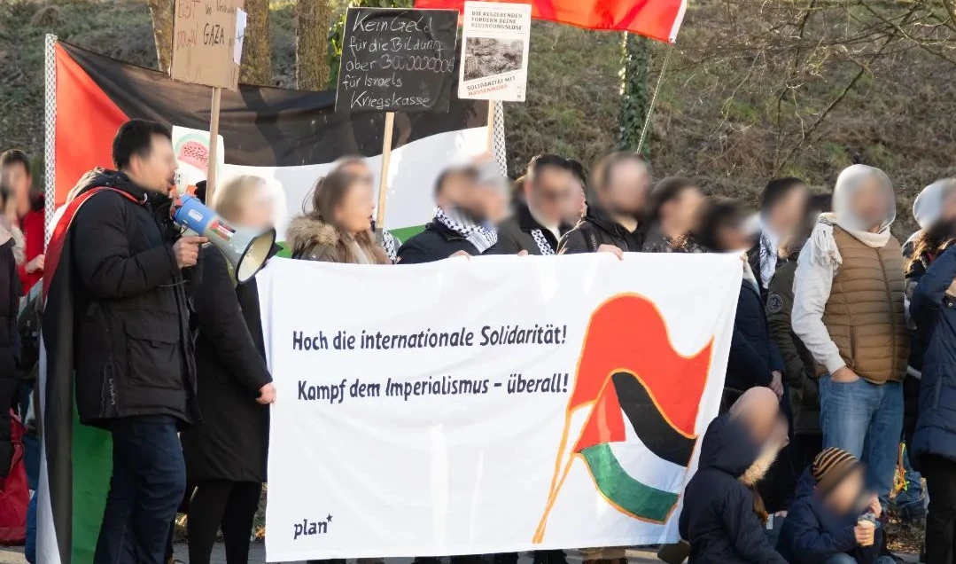 Bild von Menschen mit einem Transparent. Darauf Darstellung einer roten Fahne gekreuzt mit einer Palästina-Fahne und der Spruch &ldquo;Hoch die internationale Soldidarität! Kampf dem Imperialismus – überall!&rdquo;